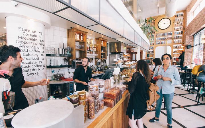 Cafetería concurrida: clientes en la barra mientras el personal los atiende