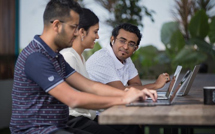 Tres colegas trabajando juntos en sus computadoras portátiles