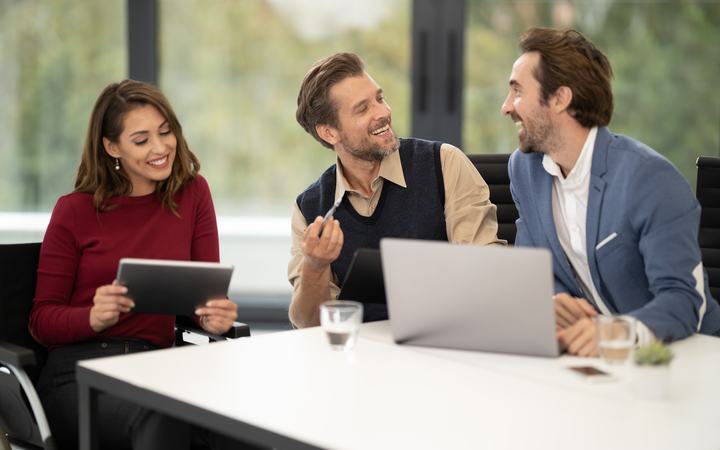 Equipo sonriente revisando avances con una tableta y una laptop